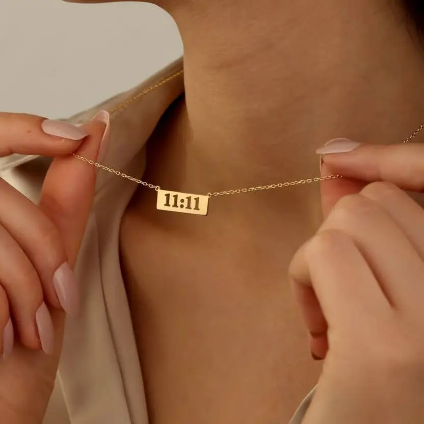 11:11 gold-tone rectangular pendant necklace worn close-up