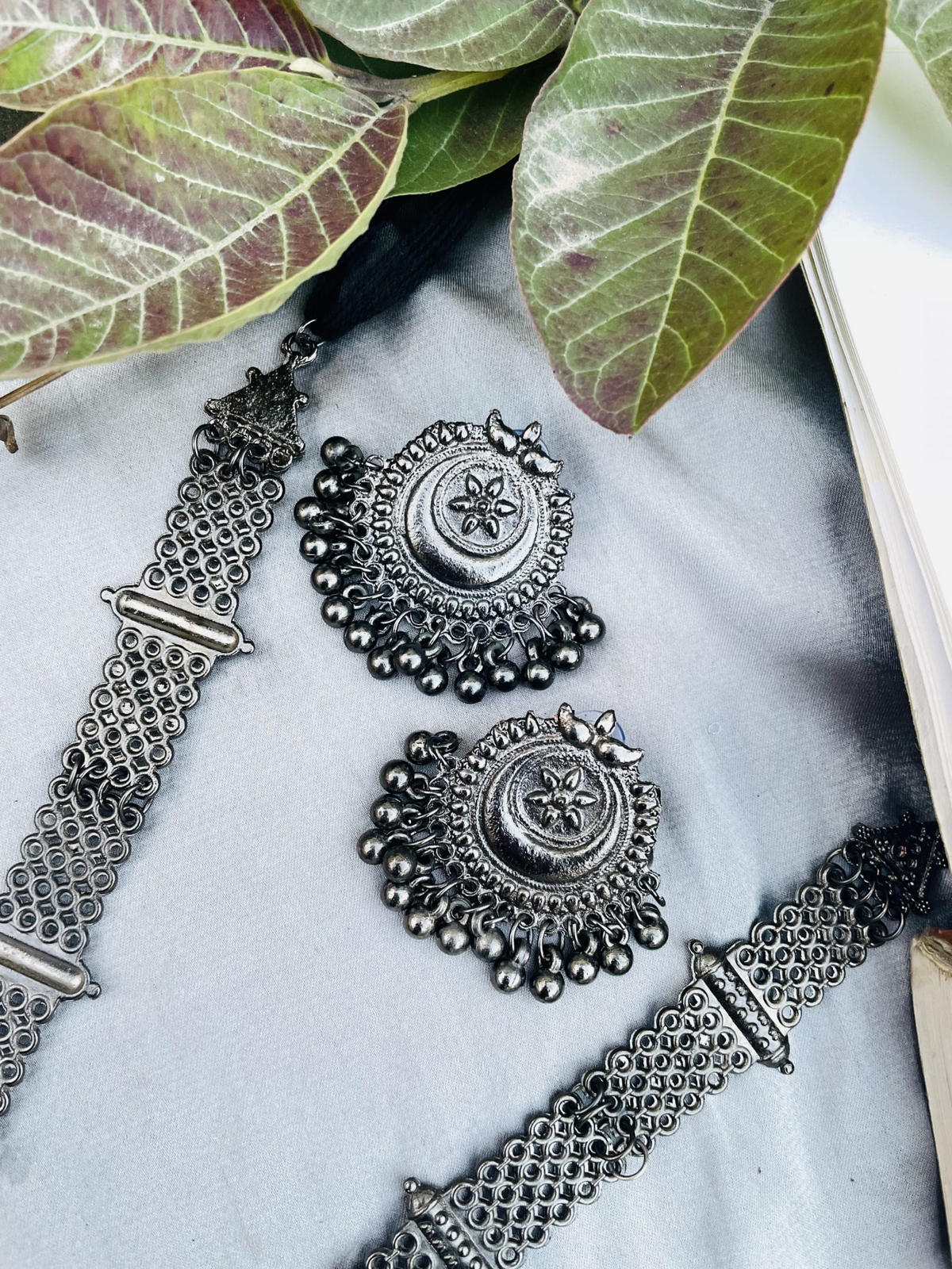 Close-up of oxidised silver-tone necklace chain and matching earrings
