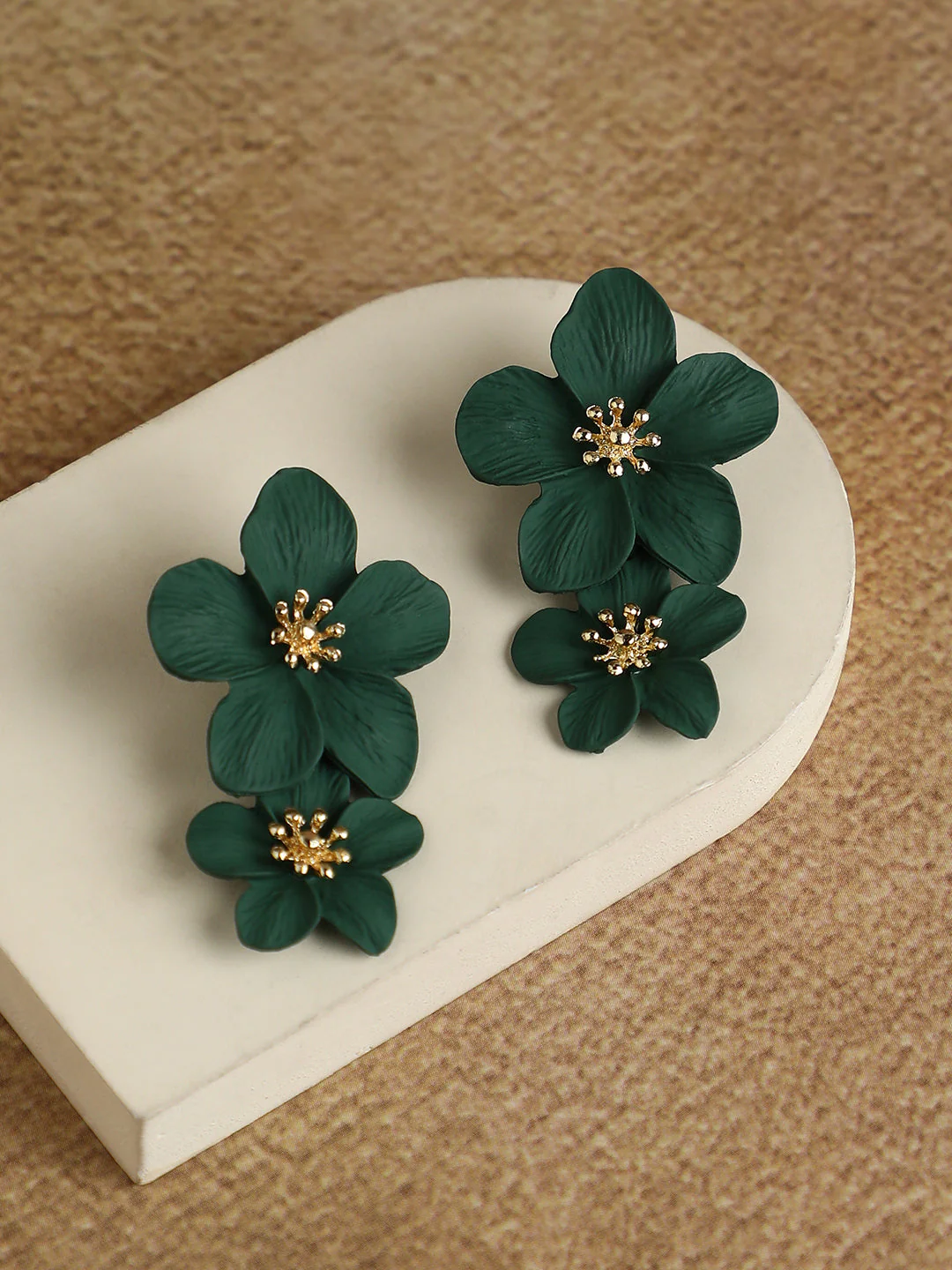 Emerald green floral dangle earrings displayed on a jewelry stand