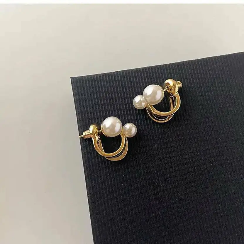 Gold-tone pearl double hoop earrings on black display