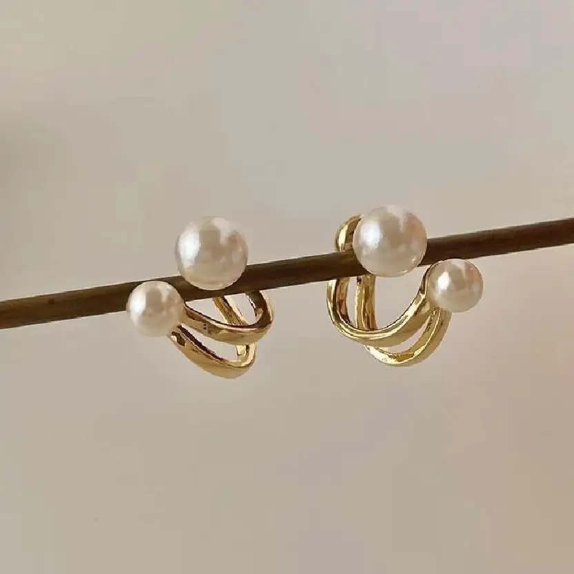 Gold-tone pearl hoop earrings hanging on rod