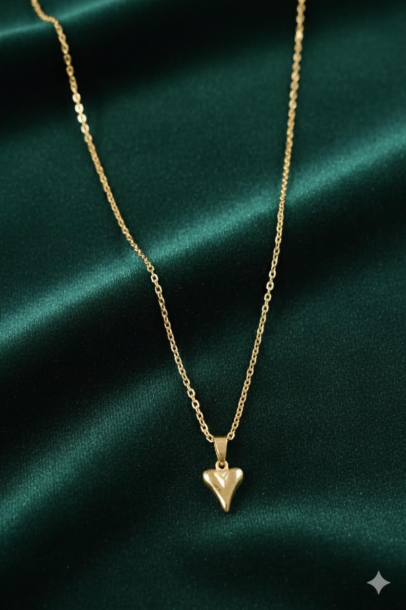 Gold-tone heart arrow pendant necklace on dark green fabric
