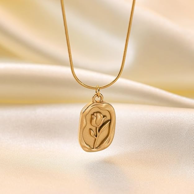 Gold-tone floral pendant necklace on light fabric