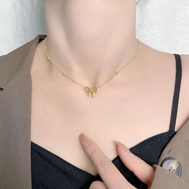 Gold-tone bow pendant necklace displayed on white background