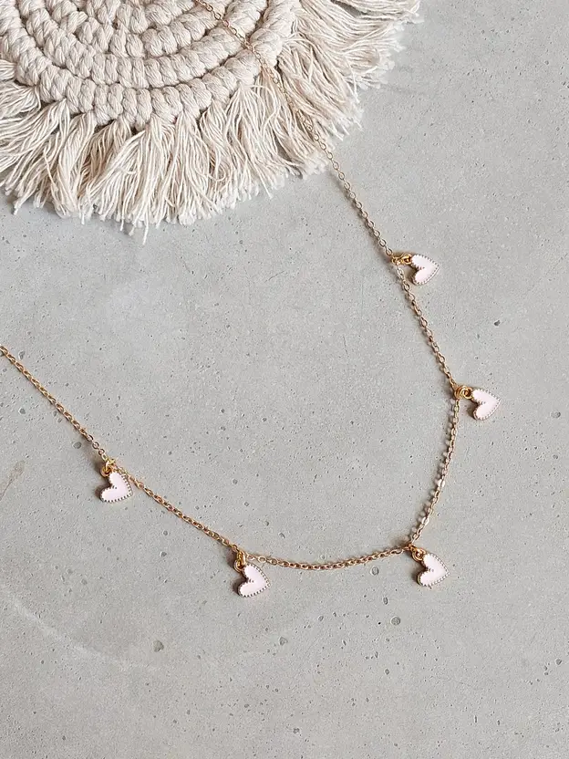 Gold-tone necklace with white heart charms displayed on card