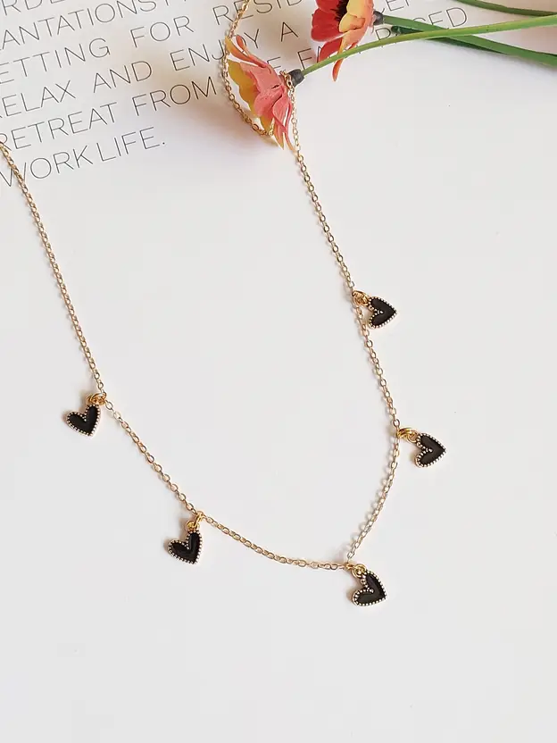 Gold-tone black heart charm necklace displayed on card