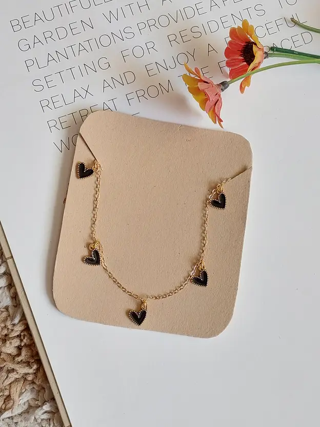 Delicate gold-tone necklace with black heart charms lifestyle display