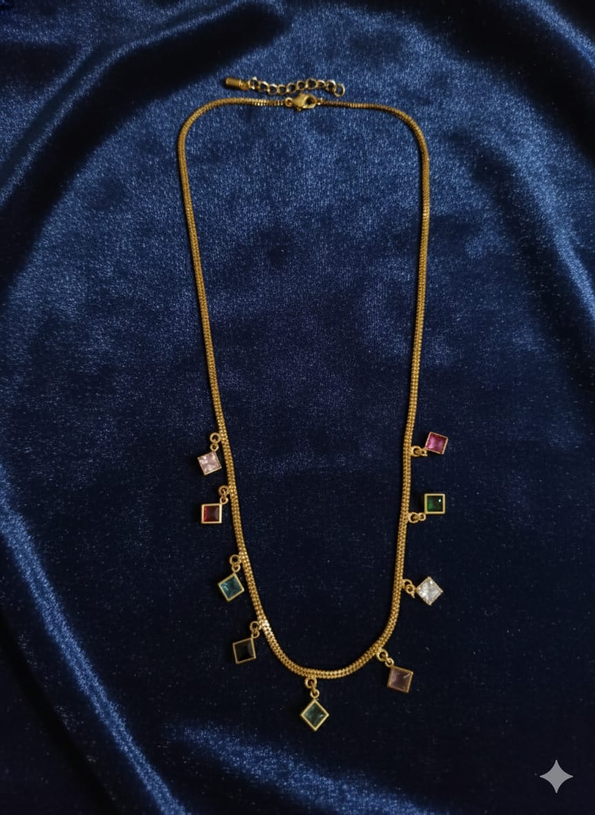 Gold-tone multicolour square charm necklace on blue fabric