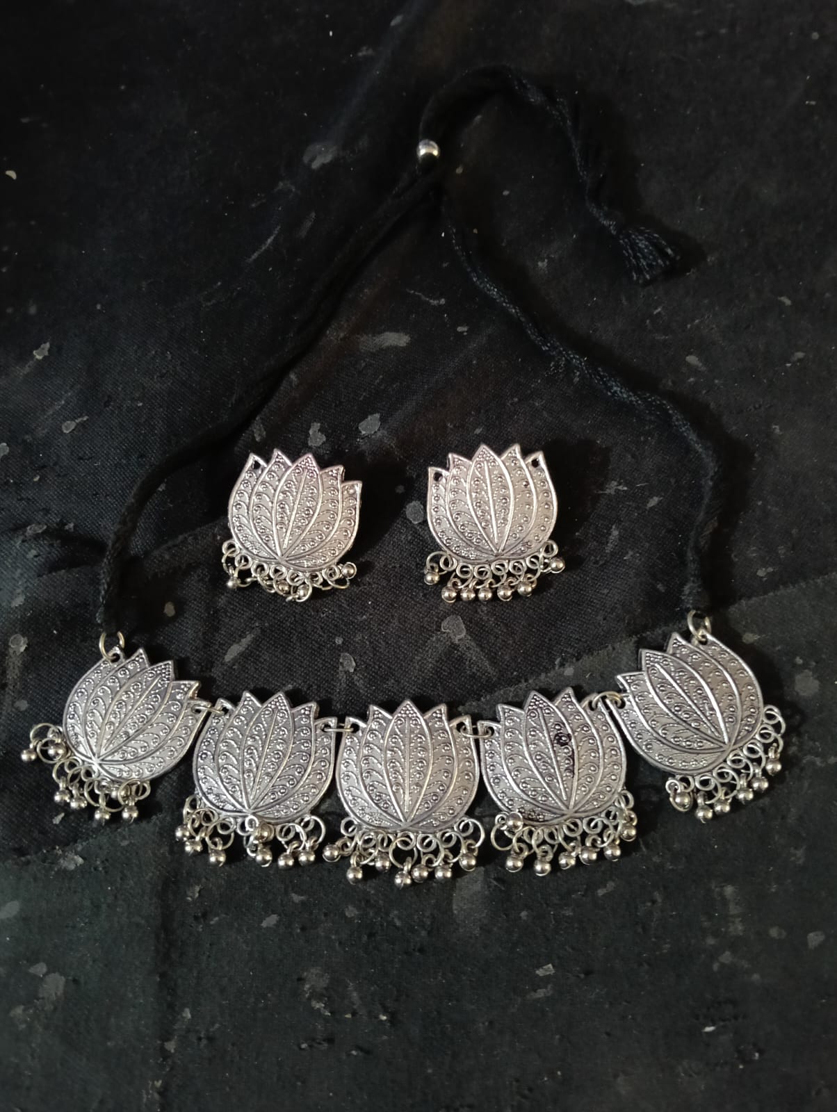 Silver oxidised lotus choker jewellery set on black background