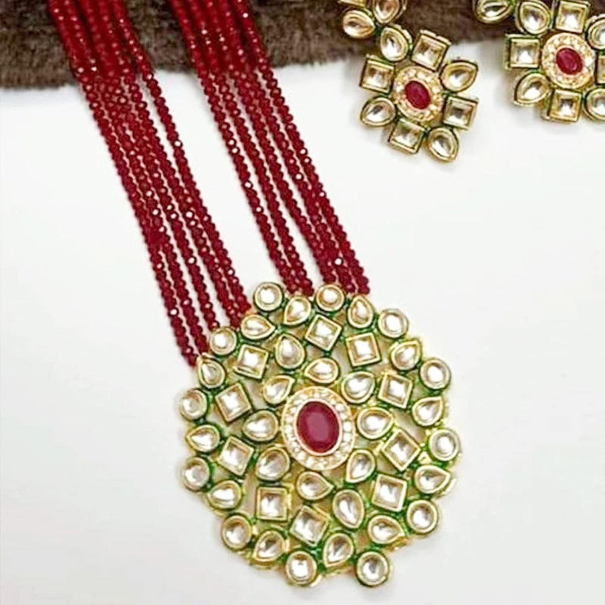 Close-up of red beaded necklace pendant with white stones and red centre stone
