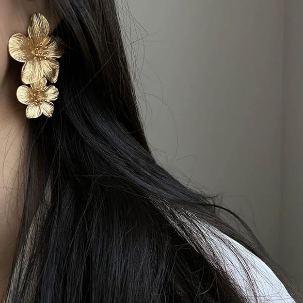 Gold-tone floral statement earrings on marble surface